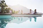 People practicing yoga at poolside