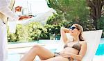 Waiter serving woman at poolside