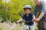 Grandfather teaching grandson to ride bicycle