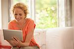 Woman using digital tablet on sofa