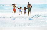 Family jumping in surf at beach