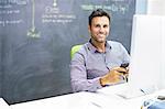 Businessman using cell phone at desk in office