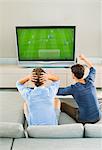 Men watching soccer game on sofa