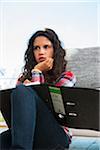 Teenage girl sitting on floor next to sofa, thinking and writing in binder, Germany