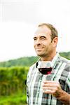 Close-up of vintner standing in vineyard, holding glass of wine, Rhineland-Palatinate, Germany
