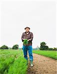 Farmer standing in field, holding plant from crop, Germany