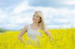 Blond young woman in blossoming rape field