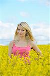 Blond young woman in blossoming rape field