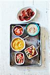 Variety of condiments in small bowls on metal tray, studio shot