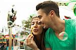 Close-up portrait of young couple blowing bubbles at amusement park, Germany