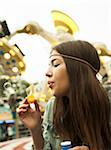 Close-up portrait of teenage girl blowing bubbles at amusement park, Germany