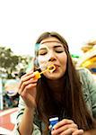 Close-up portrait of teenage girl blowing bubbles at amusement park, Germany