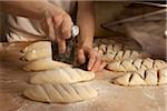 Close-up of male baker's hands cutting slits in bread dough on floured board, Le Boulanger des Invalides, Paris, France