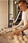 Male baker shaping bread dough by hand in bakery, Le Boulanger des Invalides, Paris, France