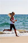 Young woman running on beach, Algarve, Portugal