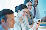 Businesswoman using cell phone in meeting