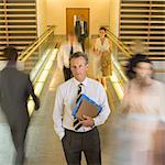 Businessman standing in busy office corridor