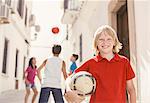 Boy holding soccer ball in alley