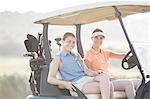 Women driving golf cart on course