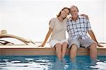 Senior couple dipping feet in swimming pool