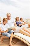 Grandparents and grandchildren using digital tablets at poolside