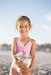 Girl holding bucket of shells on beach