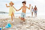 Children kicking down sandcastle on beach