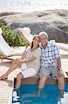 Older couple relaxing by swimming pool