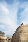 Couple sitting on rock formation on beach