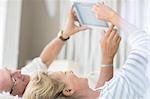 Older couple using digital tablet on bed