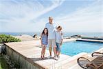 Older man and grandchildren smiling by pool