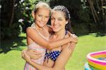 Mother and daughter hugging in backyard