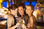 Smiling women toasting champagne glasses in nightclub