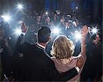 Celebrity couple waving to paparazzi at red carpet event