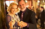 Portrait of well dressed couple toasting champagne glasses in theater lobby