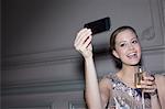 Well dressed woman with champagne taking self-portrait with camera phone