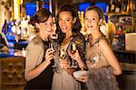 Portrait of well dressed women smiling with champagne flutes in luxury nightclub