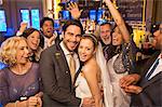 Friends cheering around smiling bride and groom at wedding reception