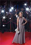 Portrait of well dressed female celebrity on red carpet with paparazzi in background