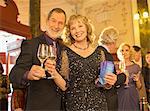 Portrait of well dressed couple toasting champagne flutes in theater lobby