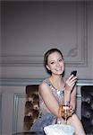 Portrait of well dressed woman drinking champagne and using cell phone