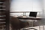 Laptop on desk in modern home office overlooking ocean