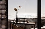 Vase of flowers on desk in modern home office overlooking ocean