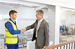 Supervisor and worker shaking hands in factory