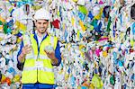 Worker holding compacted plastic bottle in recycling center