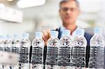 Supervisor examining bottles in factory