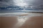 Clouds reflected in water on beach