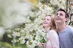 Couple smiling under tree with white blossoms