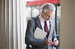 Businessman using cell phone on city street