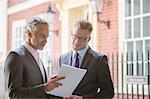 Businessmen looking at paperwork outdoors